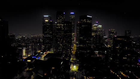 Toma-Aérea-Del-Centro-De-Los-ángeles-Por-La-Noche-Con-Rascacielos-En-El-Horizonte