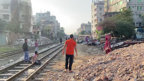 Muchachos-Jugando-Al-Cricket-Junto-A-Las-Vías-Del-Tren-En-Una-Mañana-Luminosa-En-Dhaka,-Bangladesh