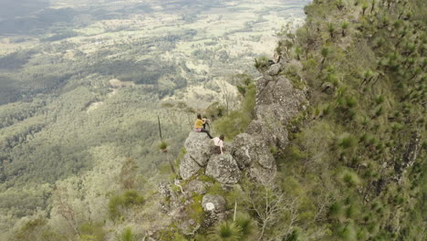 4k-Aerial-flight-above-people-resting-on-a-trail-path-with-big-rocks-on-a-mountain-spine-at-Border-Ranges-National-Park,-New-South-Wales-Australia