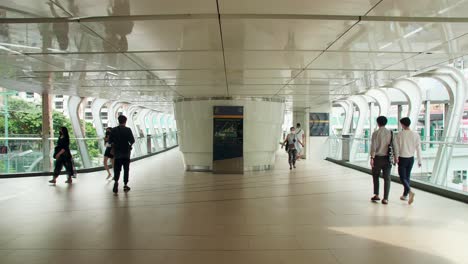 People-wearing-masks-walk-on-a-bridge-connecting-the-central-mass-transit-system-during-the-COVID-19-pandemic