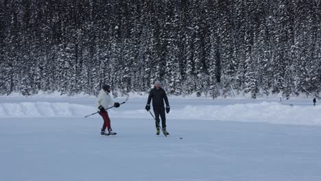 Men-playing-ice-hockey-on-frozen-lake-Louise-with-forest-as-background,-winter-scenery