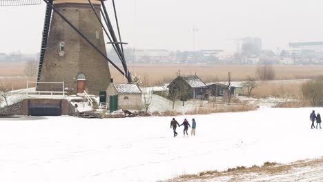 Historisches-Wahrzeichen-Von-Kinderdijk-Mit-Menschen,-Die-Neben-Windmühlen-Schlittschuh-Laufen