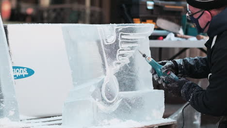 Artista-Con-Máscara-Facial-Covid-10-Usa-La-Herramienta-Dremel-Para-Dar-Forma-A-Una-Escultura-De-Hielo