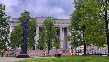 Woman-sitting-on-bench-at-Martynas-Mažvydas-Vilnius-National-Library-and-Zinia-sculpture,-Lithuania