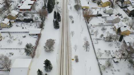 Aerial-forward-moving-tilt-view-over-Turku-suburb-in-winter-time-after-snowfall,-revealing-city-skyline