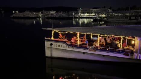 Turistas-Disfrutando-Del-Restaurante-En-Barco-Por-La-Noche-En-El-Lago-Maggiore-En-Italia