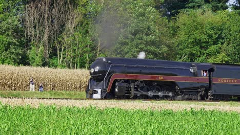 A-View-of-An-Antique-Steam-Passenger-Train,-Pulling-Out-of-a-Small-Picnic-Area,-Then-Traveling-Thru-Farmlands,-Blowing-Smoke-and-Steam-on-a-Early-Fall-Day