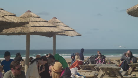 Menschen-Draußen-Genießen-Essen-Und-Tropisches-Ambiente-An-Der-Watering-Hole-Bar-Am-Perranporth-Beach,-Cornwall,-England,-Vereinigtes-Königreich-–-Teleaufnahme