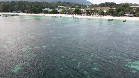 Luftaufnahme-Von-Touristen-Am-Strand-Von-Pattaya-In-Koh-Lipe,-Thailand-Bei-Sonnenuntergang-Und-Thailändischen-Booten,-Die-In-Der-Andamanensee-Verankert-Sind