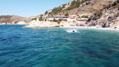 Jetski-Rápido-Navega-A-Través-Del-Mar-Azul-En-Ksamil,-Albania---Dolly-Aéreo-Hacia-Atrás