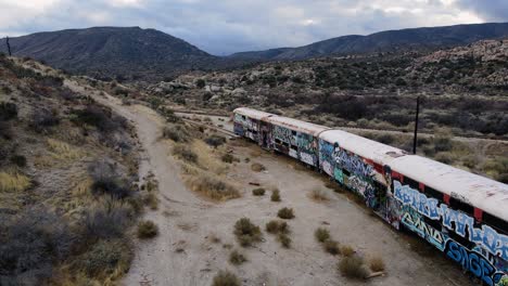 Vista-Aérea-Pasando-Un-Tren-Abandonado-En-Medio-Del-Desierto-Nublado---Inclinación,-Disparo-De-Drones