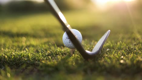 Pelota-De-Golf-Titleist-Preparada-En-Teebox-En-El-Campo-De-Golf---Primer-Plano-Con-La-Llamarada-Del-Sol-Al-Atardecer