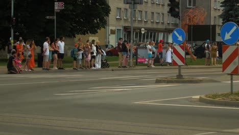 Inicio-Festivo-Del-Trofeo-Europeo-De-Rally-Fia-2022-Y-Desfile-De-Autos-En-Las-Calles-De-Liepaja,-Noche-De-La-Hora-Dorada,-Autos-De-Rally-Que-Pasan-A-Los-Espectadores,-Tiro-De-Seguimiento-De-Mano-De-ángulo-Medio