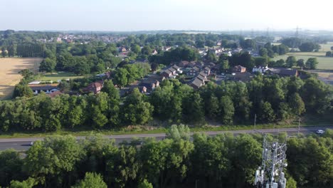 Torre-De-Transmisión-5g-En-El-Campo-Británico-Con-Vehículos-Que-Viajan-En-El-Fondo-De-La-Autopista-Vista-Panorámica-Aérea-Izquierda