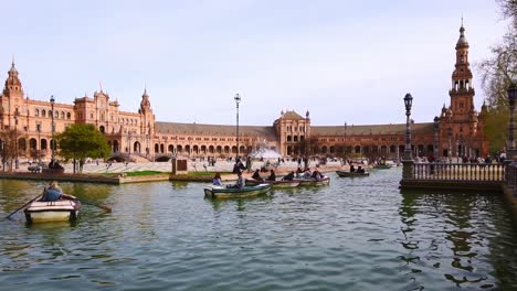 Turista-En-Botes-De-Remos-En-Los-Canales-De-Agua-Frente-A-La-Impresionante-Arquitectura-En-La-Plaza-De-España-Sevilla,-España