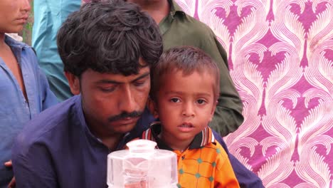 Padre-Con-Un-Niño-Pequeño-Esperando-En-El-Campamento-De-Ayuda-Contra-Inundaciones-En-Sindh,-Pakistán