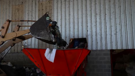 A-bulldozer's-bucket-throws-the-waste-into-a-conveyor-belt's-hopper-inside-a-waste-processing-plant