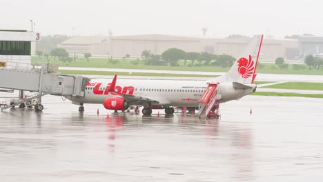 Thai-Lion-Airlines-Docken-An-Der-Halle-An,-Während-Sie-Sich-An-Einem-Regnerischen-Tag-Mit-Bodenpersonal-Auf-Dem-Internationalen-Flughafen-Don-Mueang-dmk-Auf-Den-Abflug-Vorbereiten