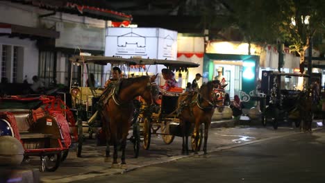 Yogyakarta,-Indonesia,-18-De-Agosto-De-2022:-Un-Carruaje-Tirado-Por-Caballos-Y-Su-Conductor-En-La-Calle-Malioboro-Están-Esperando-A-Sus-Pasajeros-En-La-Noche