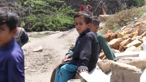 Children-Sitting-Beside-Rocks-Outside-At-Flood-Relief-Camp-In-Sinhd,-Pakistan