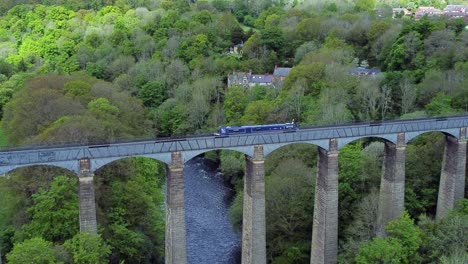 Luftaufnahme,-Die-Einem-Schmalen-Boot-Auf-Der-Überquerung-Des-Pontcysyllte-Aquädukts-Im-Trevor-Becken-In-Der-Walisischen-Tallandschaft-Folgt-Und-Langsam-Heranzoomt