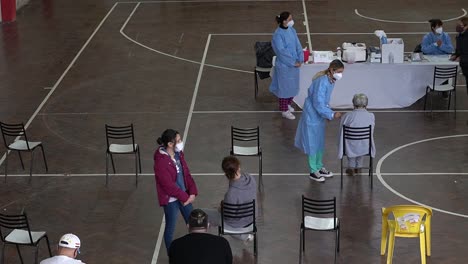 Blick-Aus-Der-Vogelperspektive-Auf-Mitarbeiter-Des-Gesundheitswesens,-Die-In-Einem-Provisorischen-Impfzentrum-Den-Covid-19-Impfstoff-Anwenden