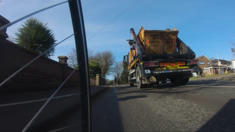 Low-Angle-POV-Cycling-On-B467-Road-Being-Overtaking-By-Skip-Lorry-In-Ickenham