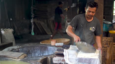 Tofu-maker-puts-soy-curd-into-wooden-mold,-traditional-Indonesian-manufacture