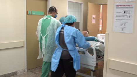 Elderly-COVID19-patient-being-moved-in-a-hospital-bed-by-nurses-in-full-protective-gear