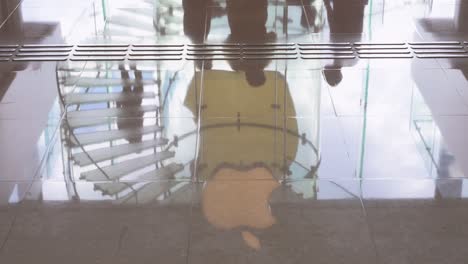 Reflection-of-shoppers-walking-past-the-American-multinational-technology-company-Apple-store-and-logo-seen-reflected-on-the-ground-in-Hong-Kong