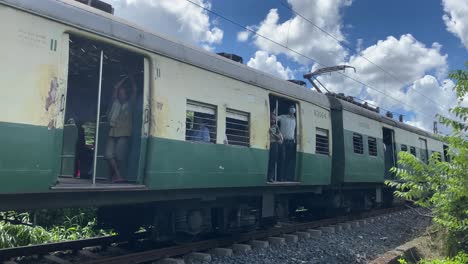 Un-Tren-Local-Verde-Y-Amarillo-Que-Circula-Por-Una-Pista-Con-Un-Hermoso-Cielo-Azul