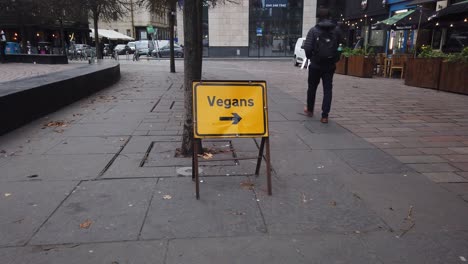 Ein-Mann-Geht-An-Einem-Gelben-Vegan-Schild-Vorbei