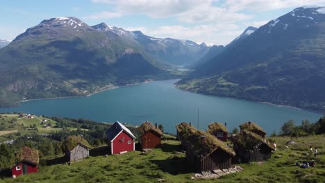 Raksetra-Loen-Antena-En-Movimiento-Hacia-Adelante-Sobre-Los-Tejados-De-Las-Cabañas-Rurales-Que-Muestran-Una-Vista-Asombrosa-De-Nordfjord-Olden-Y-Loen-En-Un-Paisaje-Montañoso---Noruega