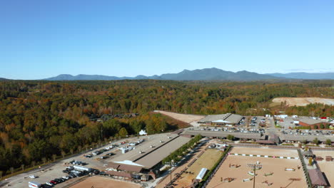 Vista-Aérea-De-Una-Instalación-Ecuestre-Con-El-Pintoresco-Paisaje-De-Carolina-Del-Norte-Al-Fondo