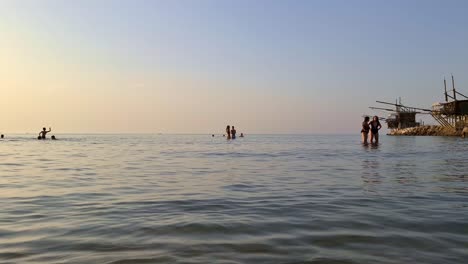 People-bathing-with-Trabucchi-or-Trabocchi-in-background,-Italy