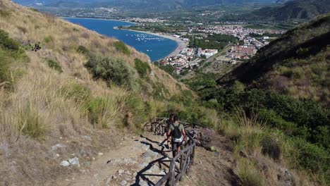 Couple-Hiking-Down-a-Rocky-Path-to-the-Coast-amongst-Rolling-Hills