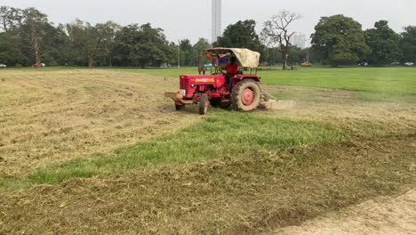 Typical-agricultural-scene-tractor-cultivation-in-field-in-clouds-of-dust-drives-off-into-the-distance-with-birches