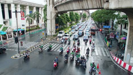 Wide-view-over-traffic-through-busy-intersections-at-rush-hour-in-Bangkok-which-is-controlled-by-traffic-lights,-there-is-heavy-traffic-every-day