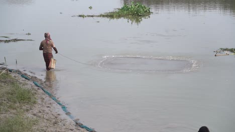 Pescador-Indio-Lanza-Red-De-Pesca-En-El-Río-Para-Atrapar-Peces,-Gente-Pobre-De-La-Clase-Trabajadora-India