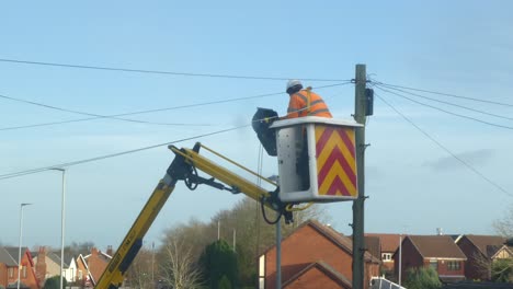 Telecom-technician-working-repairing-telephone-pole-wiring-cable-in-boom-crane-basket