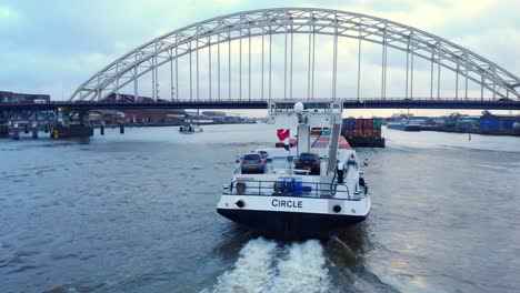 Luftaufnahme-Des-Hecks-Eines-Kreisförmigen-Binnencontainerschiffs,-Das-Unter-Brug-über-De-Noord-Fährt