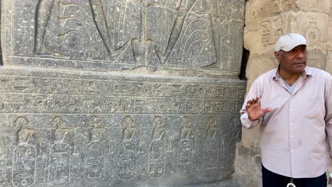 4K-Video-Eines-ägyptischen-Reiseführers,-Der-Touristen-Die-Bedeutung-Der-ägyptischen-Hieroglyphenkartuschen-Erklärt,-Die-In-Eine-Wand-Im-Luxor-Tempel-Geschnitzt-Sind