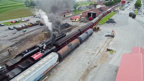 An-Aerial-View-of-an-Antique-Steam-Passenger-Train-Waiting-for-a-Second-Steam-Train-To-Pass-Blowing-Smoke