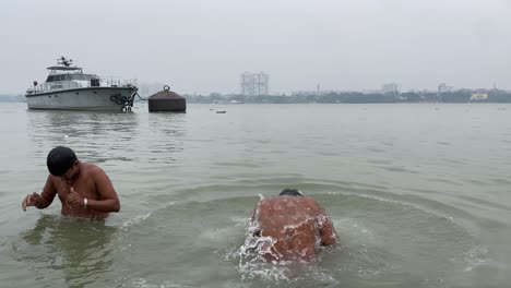 Close-up-view-of-people-seen-in-the-shot-bathing-in-the-Ganges-river-at-sunrise-in-Kolkata,-West-Bengal,India