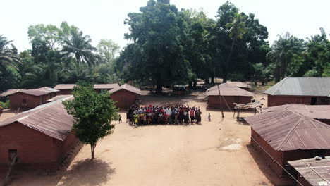 Villagers-form-up-to-wave-to-the-drone-as-it-pulls-back-to-reveal-Olegobidu-village-in-Benue-State,-Nigeria