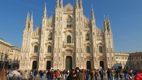 Tilt-down-of-Asian-tourist-taking-picture-of-woman-with-protective-mask-at-famous-Duomo-di-Milano-or-Milan-Cathedral-in-Italy