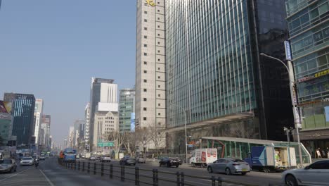 City-public-buses-departing-one-after-another-from-Gangnam-bus-station-on-a-sunny-day-with-Seoul-urban-skyline