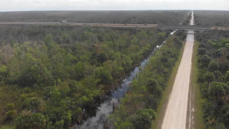 Puente-De-La-Carretera-Sobre-El-Canal-Camino-De-Tierra-Paso-Elevado-Autopista-De-Los-Everglades-Florida-Inclinación-Aérea-Del-Dron