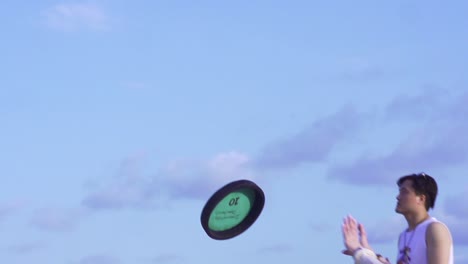 Slow-motion-shot-of-Frisbee-spinning-in-the-air-and-caught-by-Asian-woman-wearing-hot-pants-on-the-beach