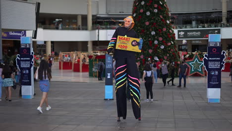 Zancudos-Con-Máscara,-Acróbata-Disfrazado-En-Un-Centro-Comercial-Junto-Al-árbol-De-Navidad